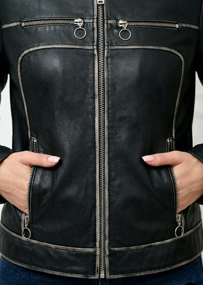 Close-up of a black leather jacket with zippers and hands in the pockets.