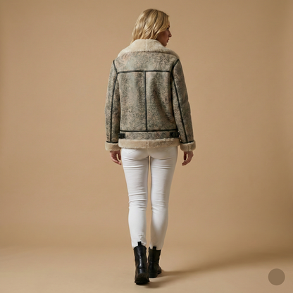 Woman wearing a patterned jacket and white pants on a beige background