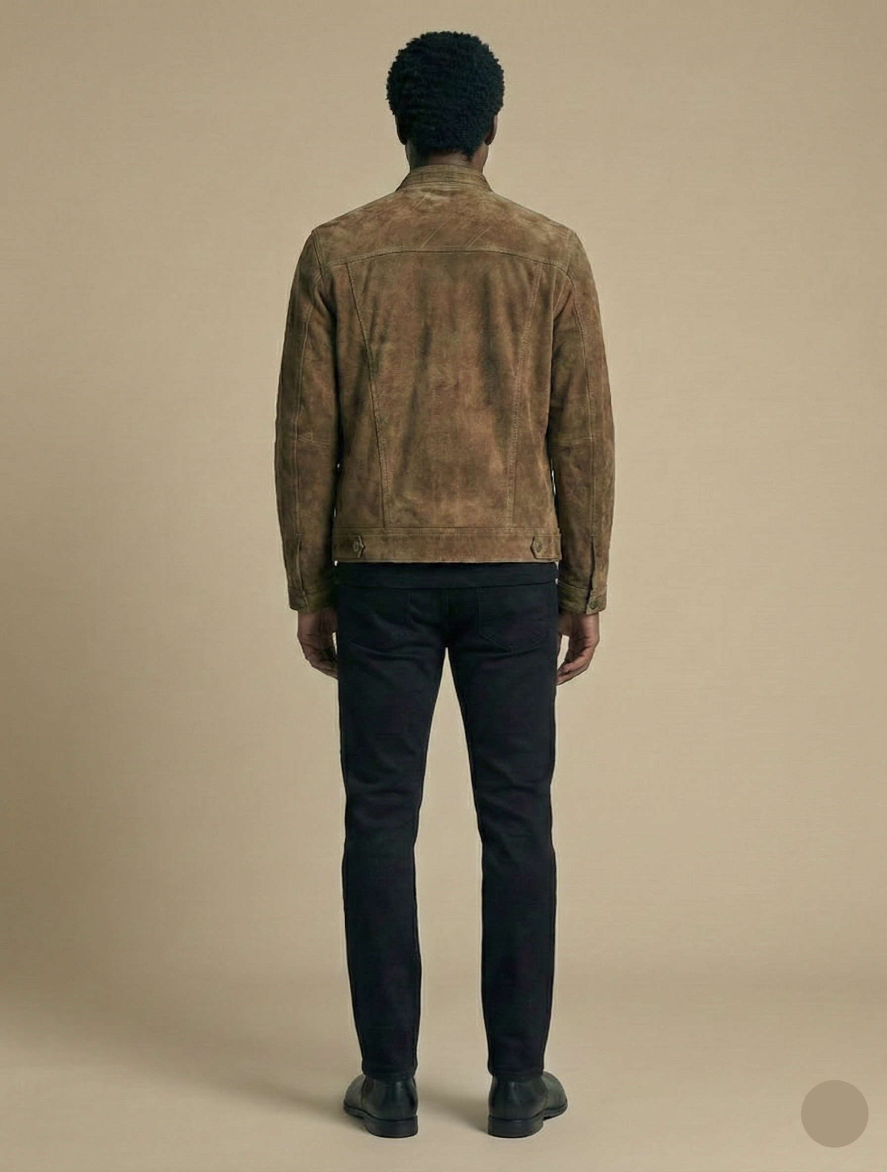Man wearing a brown suede jacket and black pants on a beige background
