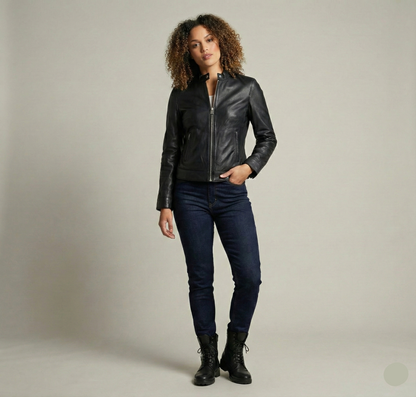 Woman wearing a black leather jacket, dark jeans, and black boots on a plain background