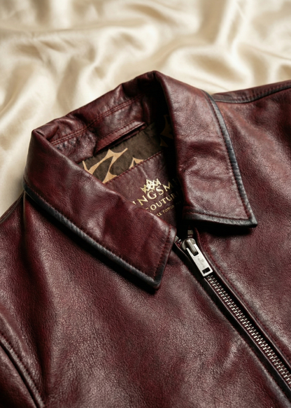 Close-up of a brown leather jacket with a brand logo on a beige fabric background